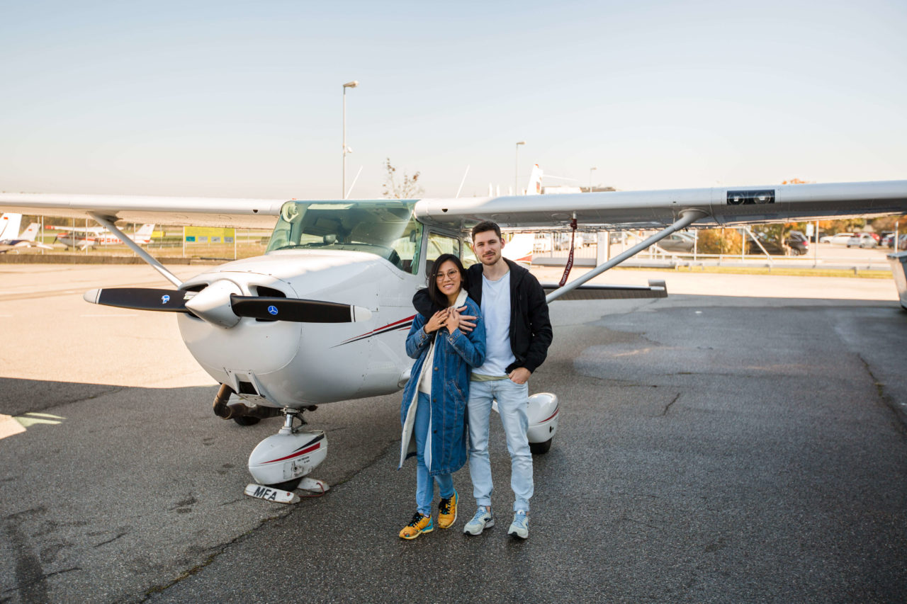 Photo d'un couple devant un avion, sur le tarmac